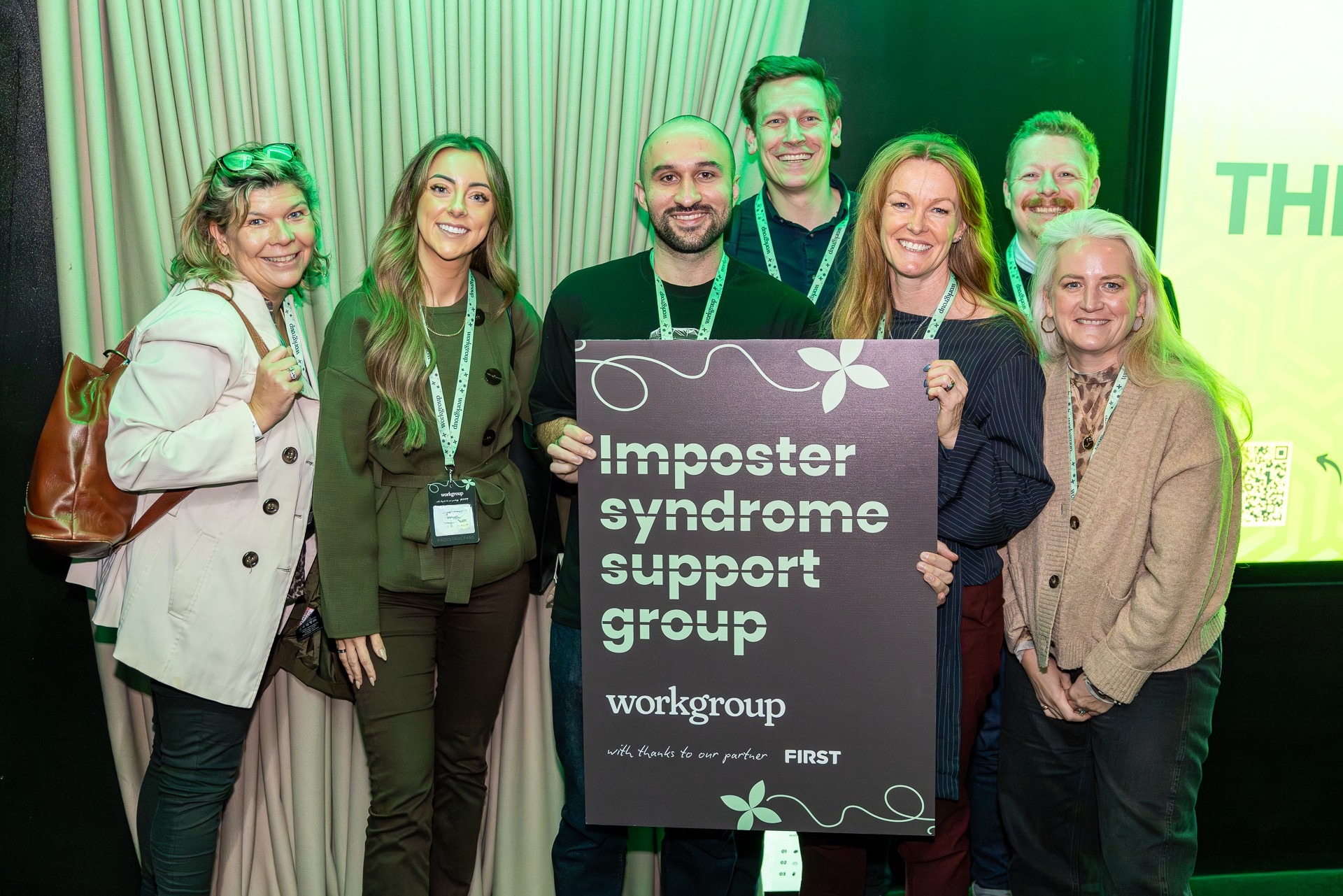 Attendees at a Workgroup CMO event holding an ‘Imposter syndrome support group’ sign